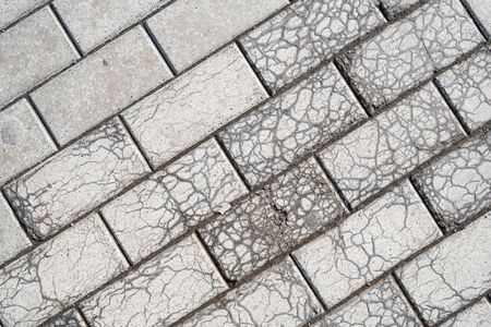 Background image of pavement cover. Detailed texture of paving slabs. Text space. Wallpaper. Footpath cover. Texture for the exterior. Tiled masonry destroyed by plants. Cracks on the paving slabs.の写真素材