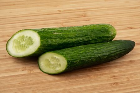 Cucumber on a wooden background. Wooden plank. Harvest fresh cucumbers. Ripe vegetable. Wood texture. Green smooth skin. A slice of cucumber. Vegetable diet. Proper nutrition. Ingredient for the saladの写真素材