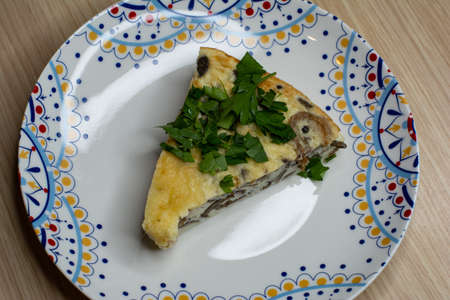 Triangular piece of omelet with mushrooms sprinkled with herbsの写真素材