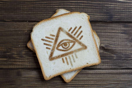 toast with the sign of the eye on dark wood. Conspiracy theory. Big brother is watching you.の写真素材