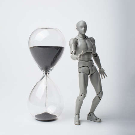 Male figurine and hourglass. It's time to act! manage your time. now or never.の写真素材