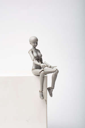 A female figurine with a pistol in her hands sits on a plaster cube. Woman take aim with a pistol. Self defense with firearms.の写真素材