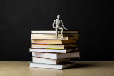 A stack of books lies on a plywood sheet. A man sits on a stack of books. Composition in the dark...