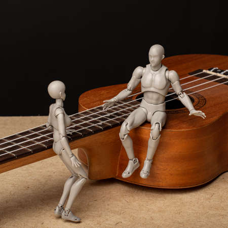 A man and a woman are talking. The man is sitting on the ukulele. composition with figures of people. The woman leaned on the neck of the ukulele.の写真素材
