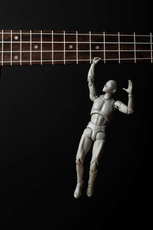 A man hangs on the strings of a ukulele. The man gripped the string tightly. Music in our hearts.の写真素材