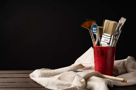 A glass with brushes stands on a light-colored rag. Two brushes lie in front of the glass.の写真素材