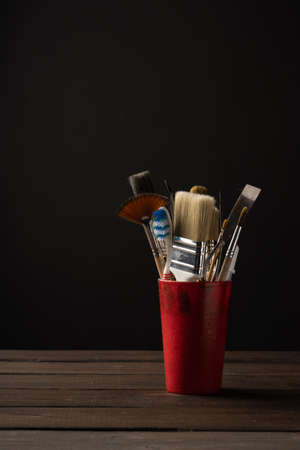 A glass with brushes stands on a wooden surface on a dark backgroundの写真素材