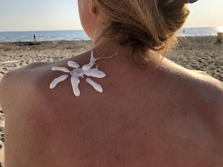 Female using sun cream on the beach.の写真素材