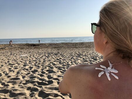 Female using sun cream on the beach.の写真素材