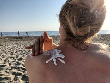 Female using sun cream on the beach.の写真素材
