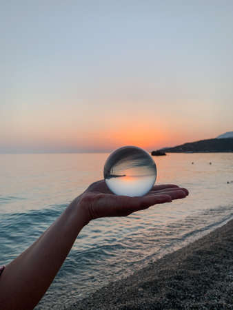Beautiful sunset view through lens of crystal ball on water horizonの写真素材