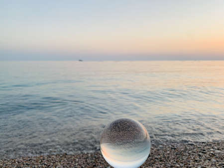Beautiful sunset view through lens of crystal ball on water horizonの写真素材