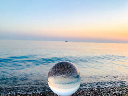 Beautiful sunset view through lens of crystal ball on water horizonの写真素材
