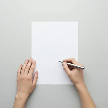 Female hands holding blank sheet of paper on grey background, top viewの素材