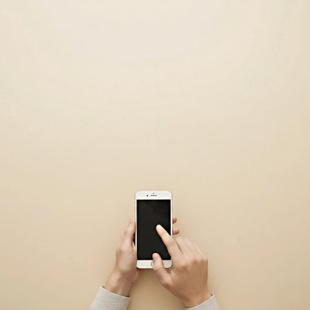Person using a smartphone on a beige background, top view with copy spaceの素材