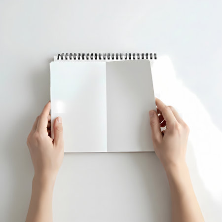 Female hands holding blank notebook on white background, top view. Mockup for designの素材