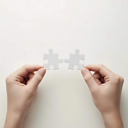Hands connecting two jigsaw puzzle pieces on white background. Teamwork conceptの素材