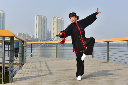 Luannan County, Hebei Province, China - May 11, 2019:  an Asian woman practices Chinese Taijiquan in a park as a fitness exercise.のeditorial素材