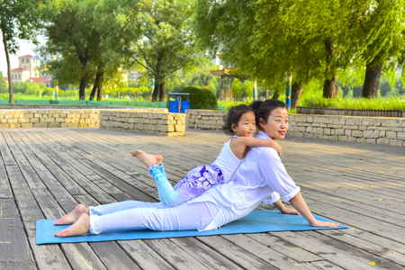 Luannan County, Hebei Province, China - June 21, 2019. On the International Yoga Day, a woman led her daughter to perform yoga in Luannan Park.のeditorial素材