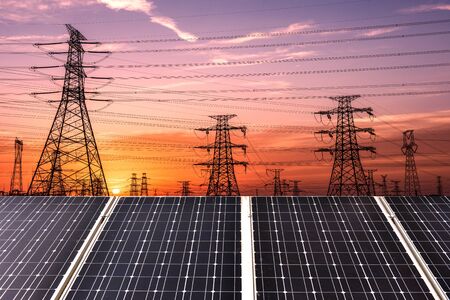 Solar panels, photovoltaics and transmission towers at sunset.