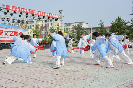Luannan County, Hebei Province, China - August 8, 2019. A group of women performing Chinese Taiji Kung Fu Fan in the squareのeditorial素材