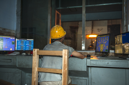 Luanan county, hebei province, China -- June 14, 2014: steelworkers work in the control room and workshop of a steel mill.のeditorial素材