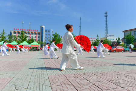 Luannan county, hebei province, China -- August 9, 2018: organized women practice Chinese tai chi and fan dance for fitness at the city squareのeditorial素材