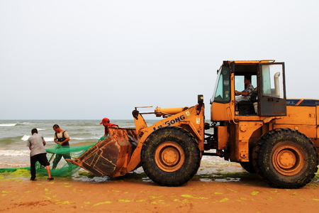 Fishermen pulling a fishing net on to shoreの写真素材
