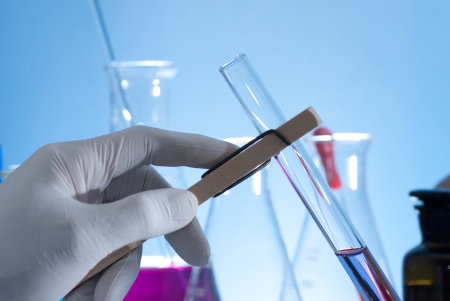 Hand holding a test-tube by test tube holderの写真素材