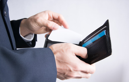 A man put a white business card into his wallet