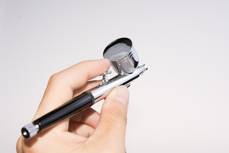 Airbrush on a white background with a hand.の写真素材