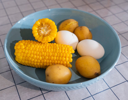 A simple breakfast consisting of 4 potatoes, halved corn, and two eggs.の写真素材