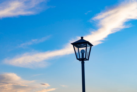 Under the blue sky, the street lights on the bridge are waiting for the night to come.の写真素材