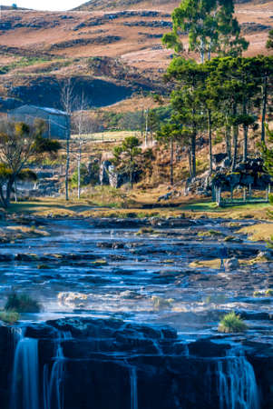 Rural landscape with river, waterfall, pine trees and field in the Santa Catarina mountain range.の写真素材