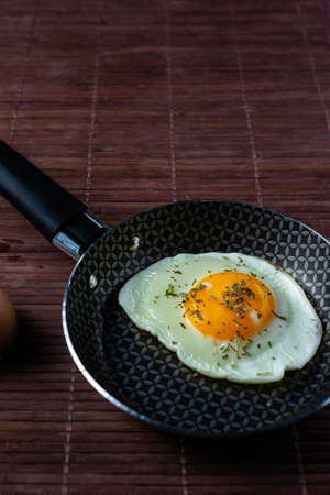 Frying pan with fried egg on a bamboo table.の写真素材