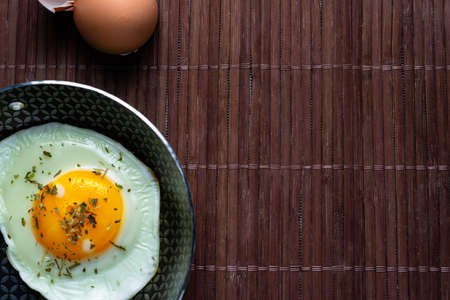 Frying pan with fried egg on a bamboo table.の写真素材
