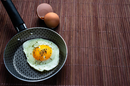 Frying pan with fried egg on a bamboo table.の写真素材