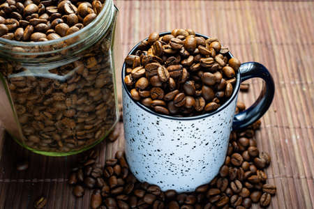Mug and glass jar with coffee beans on bamboo background.の写真素材