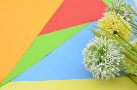 green, white and yellow artificial flower on orange, red, blue and green background give romantic look conceptの写真素材