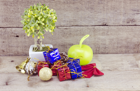 vantage look Christmas decorations with red ball,green ball,red ribbon,bell,samll tree on white pot, and artificial flower. aged and dirty wood background with textureの写真素材