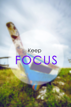 Motivation word KEEP FOCUS with blurred image of Malaysian traditional fisherman boat. Green grass and dramatic cloudの写真素材
