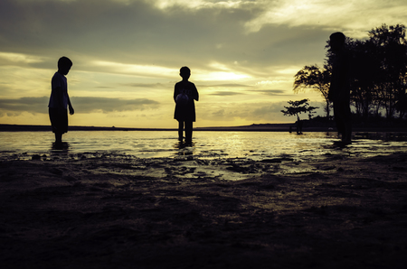 silhouette image concept young boy standing at the beach  with sunrise backgroundの写真素材