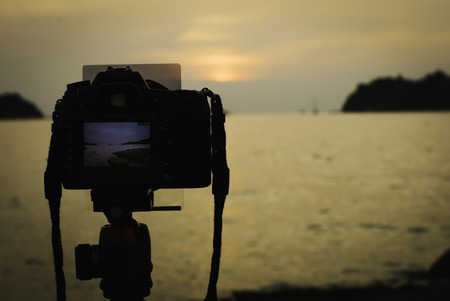 silhouette image of digital camera on tripod during sunset.sea and island background.copy space to the rightの写真素材