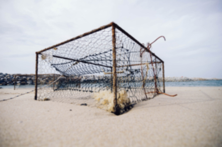 closeup rusty crab pots on the sandy beach over blurred water break background.focus in the middle.shallow depth of field.color toning effectの写真素材