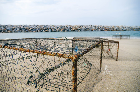 closeup rusty crab pots on the sandy beach,water break and white cloudy sky. focus in the middle.shallow depth of fieldの写真素材