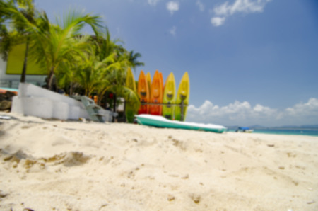 surface level shot and blurred image of beautiful beach scenery, kayaks stack on white sandy beach at sunny day. clear sea water with cloudy clouds and blue sky.の写真素材