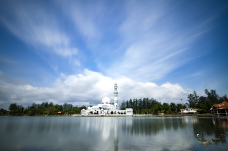 blurred image of white floating mosque with motion cloud and blue sky at sunny day.soft focus image...