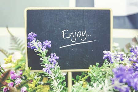 conceptual image, word ENJOY on wooden blackboard. blurred background and faded color tone effectの写真素材