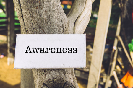 healthy lifestyle concept, word awareness on white canvas and wood pole over blurred cottage backgroundの写真素材