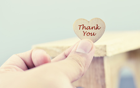 conceptual image,romantic look hand holding heart made from wood with word THANK YOU over blurred and selective focus backgroundの写真素材